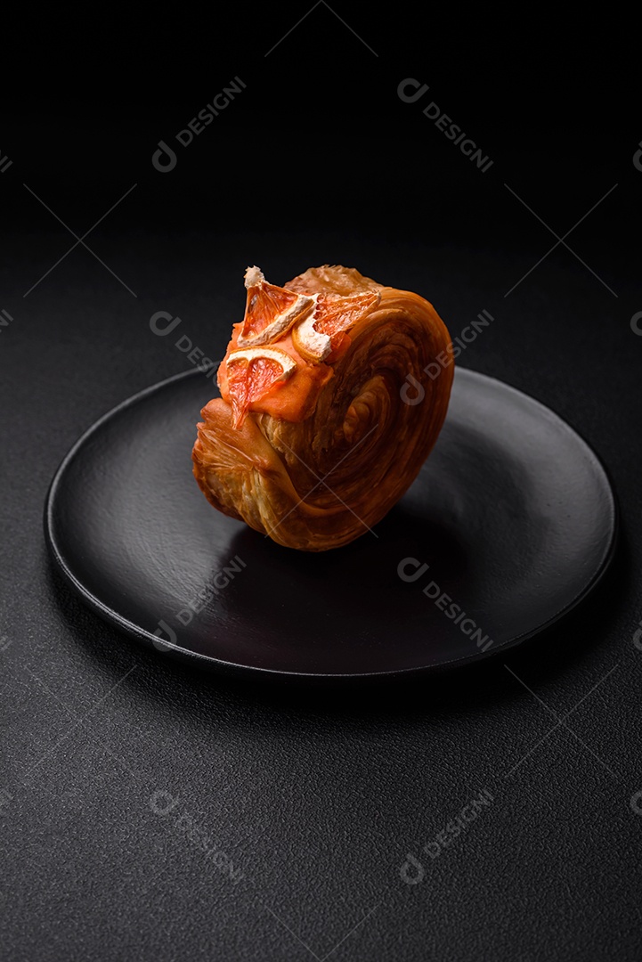 Croissant redondo de massa folhada com recheio de frutas cítricas ou rolo de Nova York sobre fundo escuro de concreto