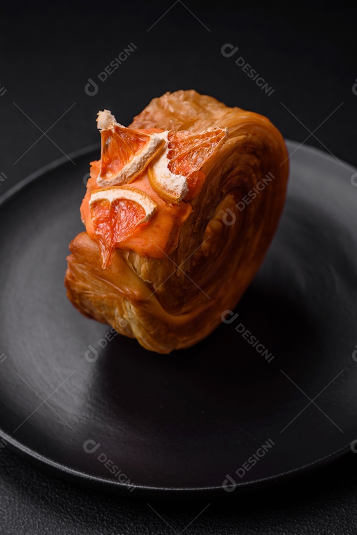 Croissant redondo de massa folhada com recheio de frutas cítricas ou rolo de Nova York sobre fundo escuro de concreto