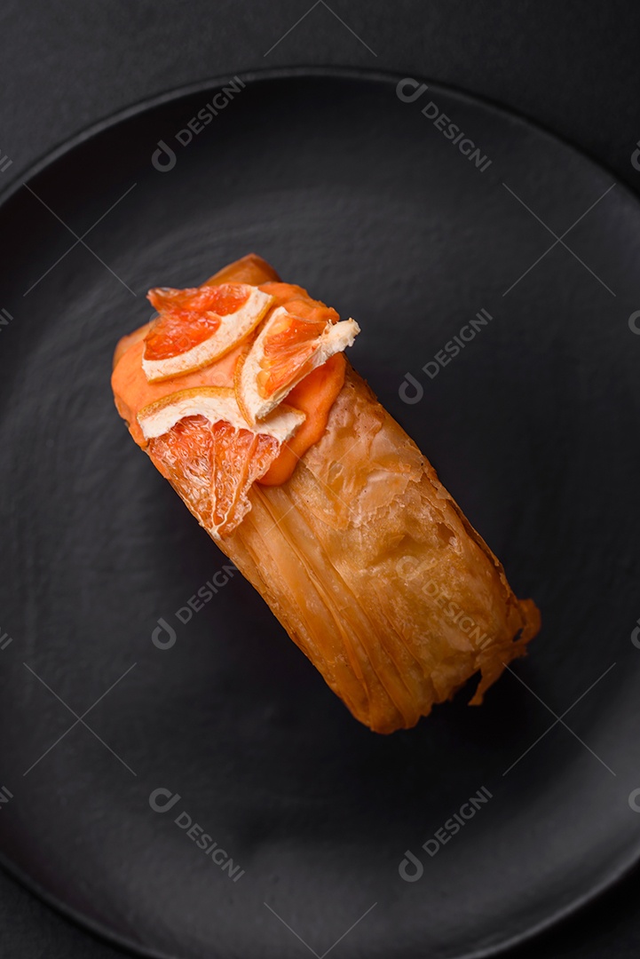 Croissant redondo de massa folhada com recheio de frutas cítricas ou rolo de Nova York sobre fundo escuro de concreto