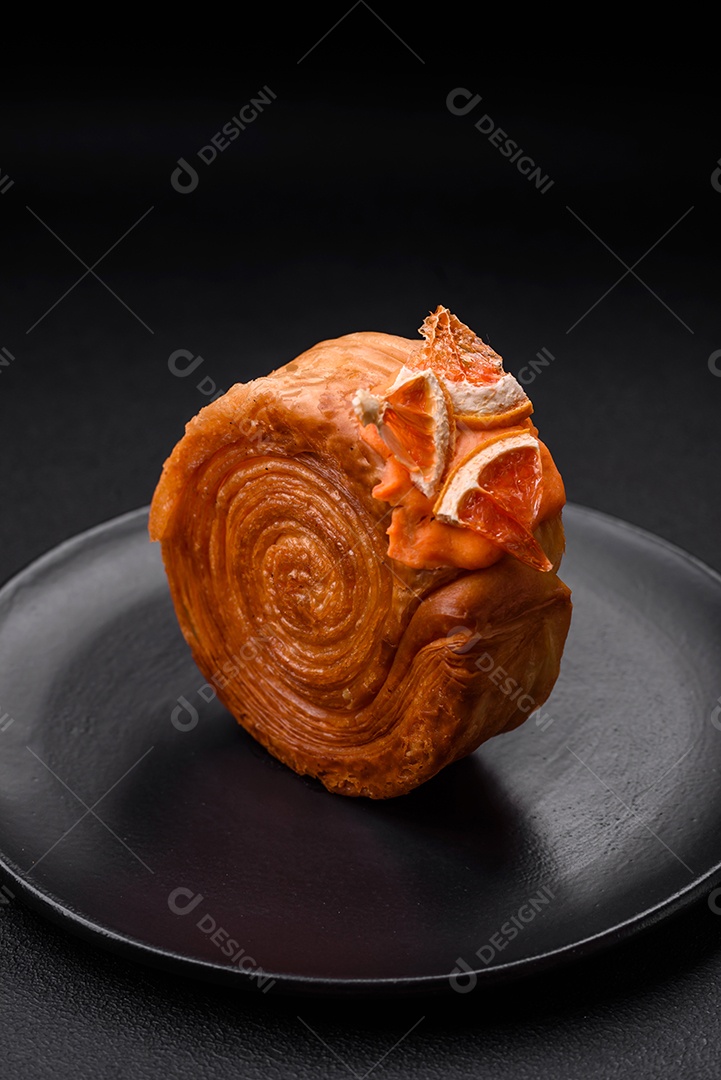 Croissant redondo de massa folhada com recheio de frutas cítricas ou rolo de Nova York sobre fundo escuro de concreto