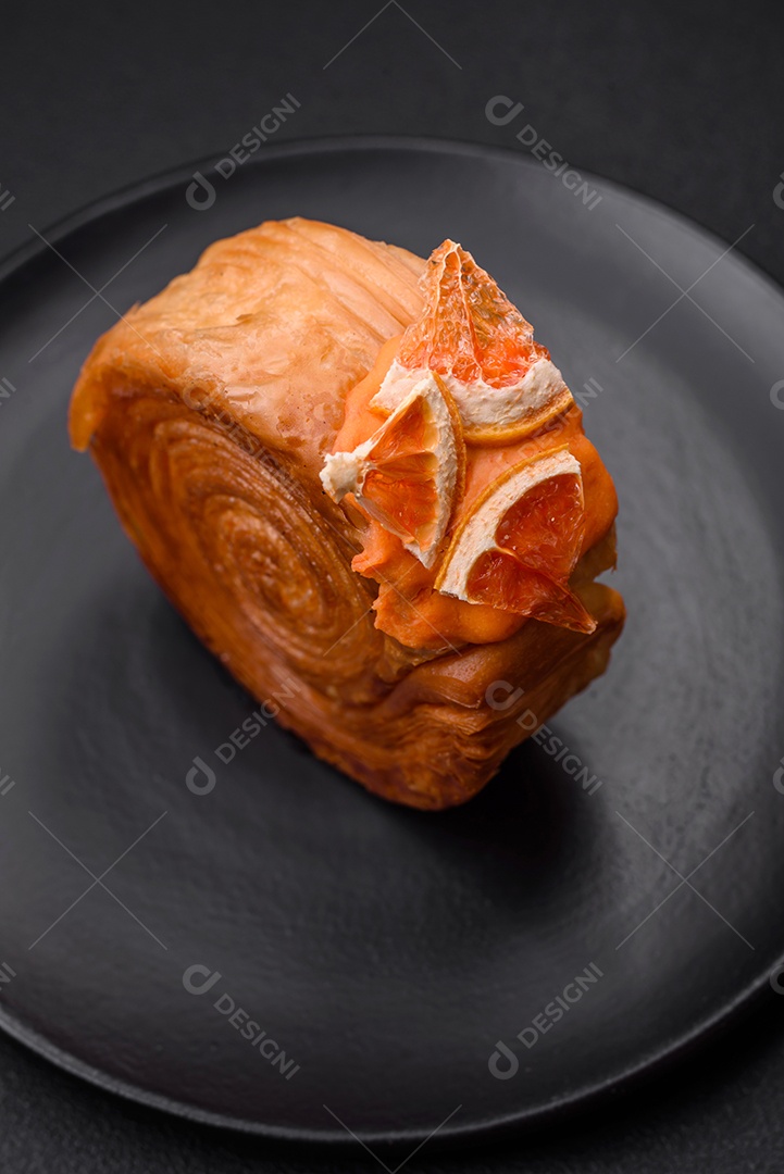 Croissant redondo de massa folhada com recheio de frutas cítricas ou rolo de Nova York sobre fundo escuro de concreto