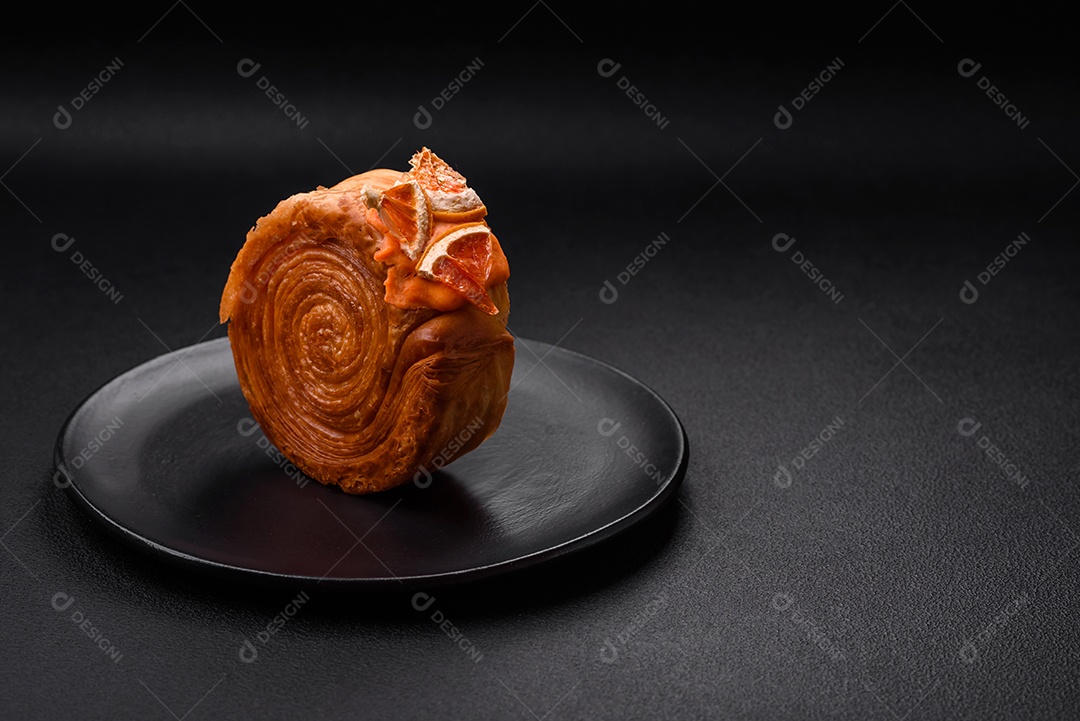 Croissant redondo de massa folhada com recheio de frutas cítricas ou rolo de Nova York sobre fundo escuro de concreto