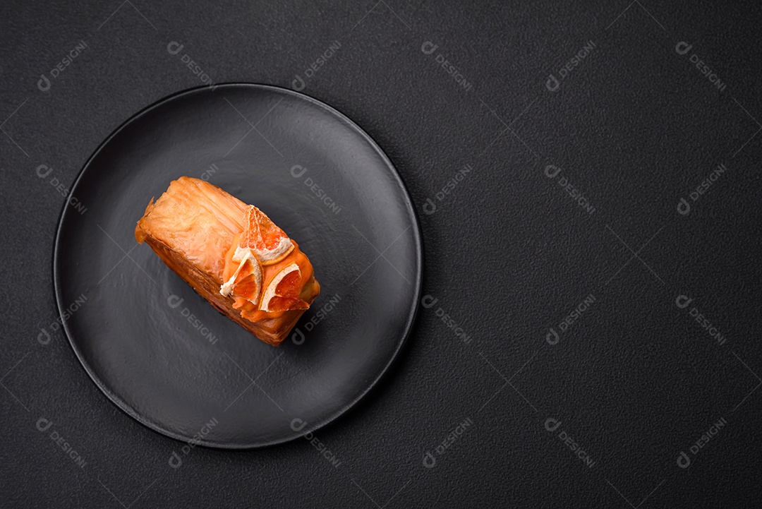 Croissant redondo de massa folhada com recheio de frutas cítricas ou rolo de Nova York sobre fundo escuro de concreto