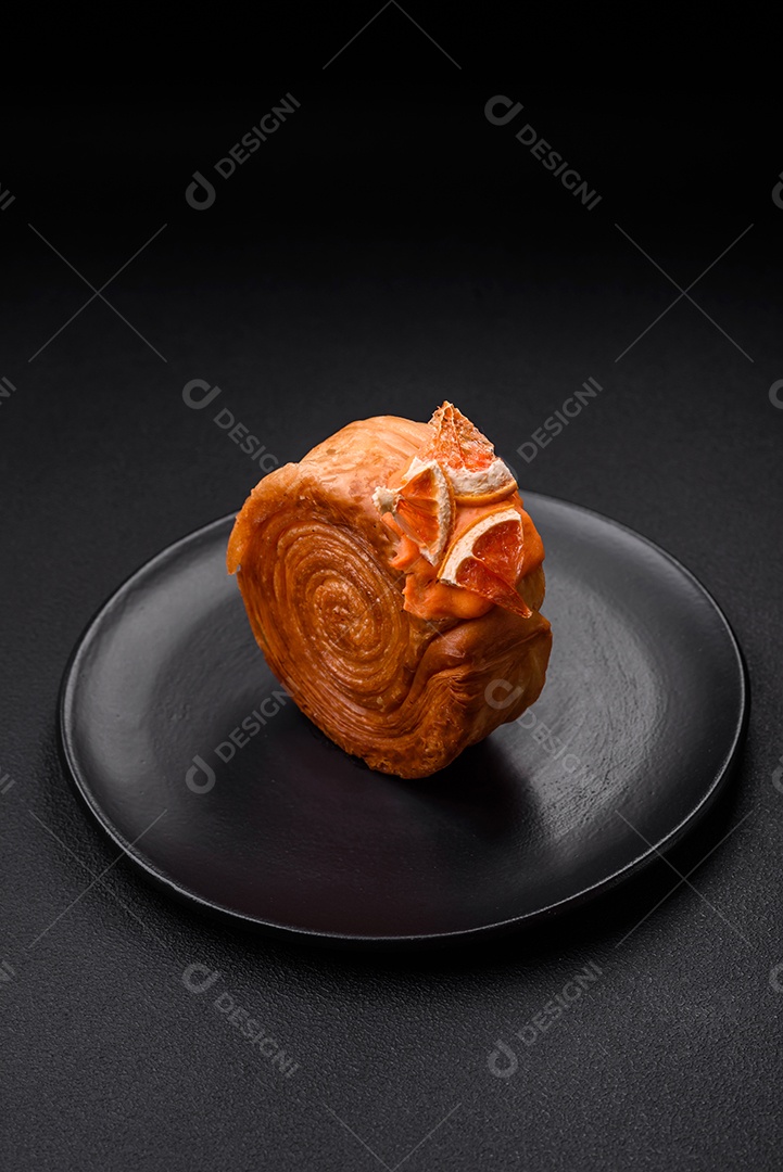 Croissant redondo de massa folhada com recheio de frutas cítricas ou rolo de Nova York sobre fundo escuro de concreto
