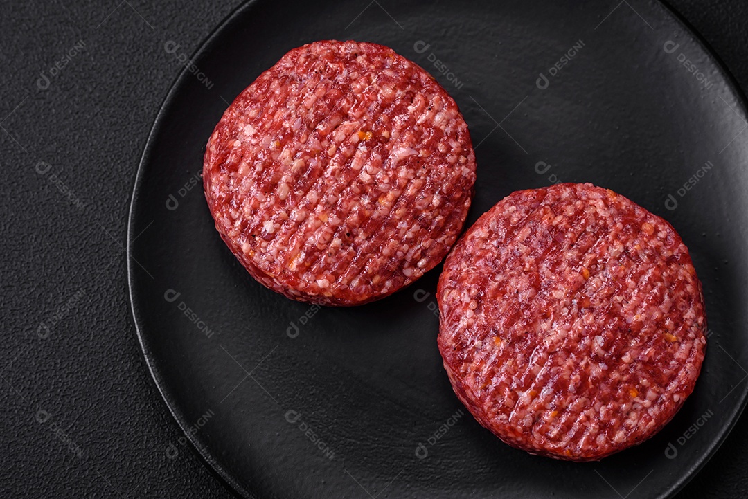 Hambúrguer de carne moída crua fresca com sal e especiarias em fundo de concreto texturizado