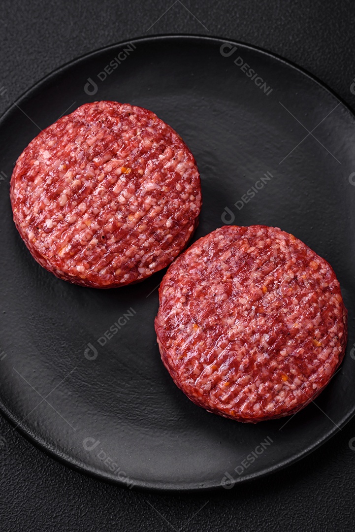 Hambúrguer de carne moída crua fresca com sal e especiarias em fundo de concreto texturizado