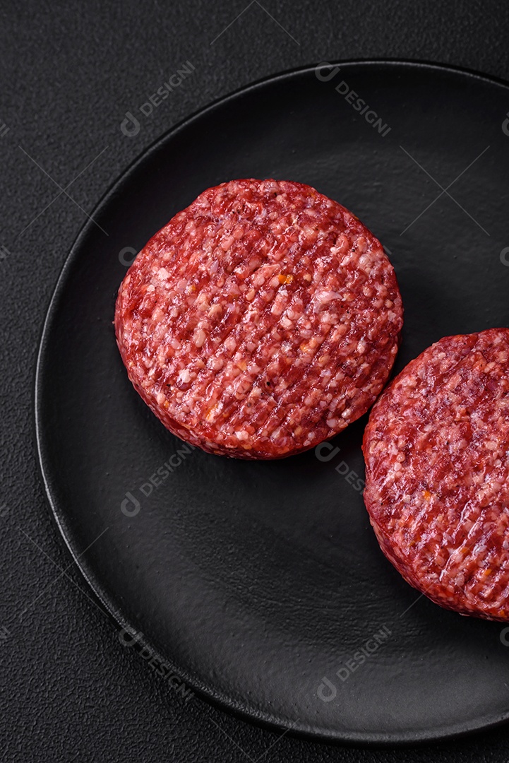 Hambúrguer de carne moída crua fresca com sal e especiarias em fundo de concreto texturizado