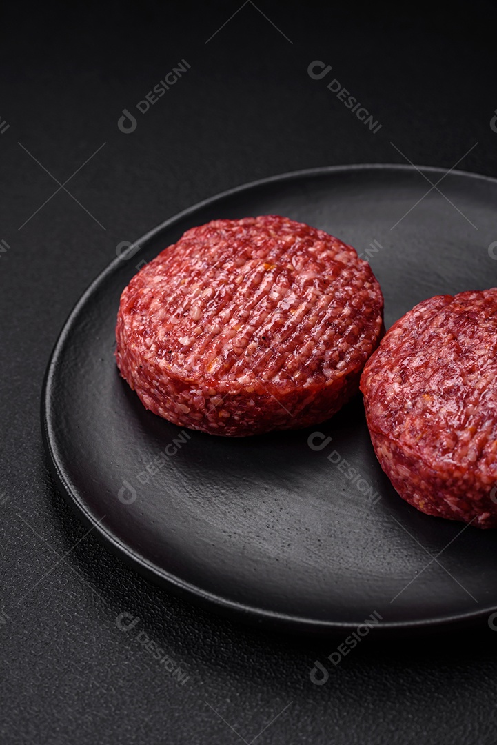 Hambúrguer de carne moída crua fresca com sal e especiarias em fundo de concreto texturizado