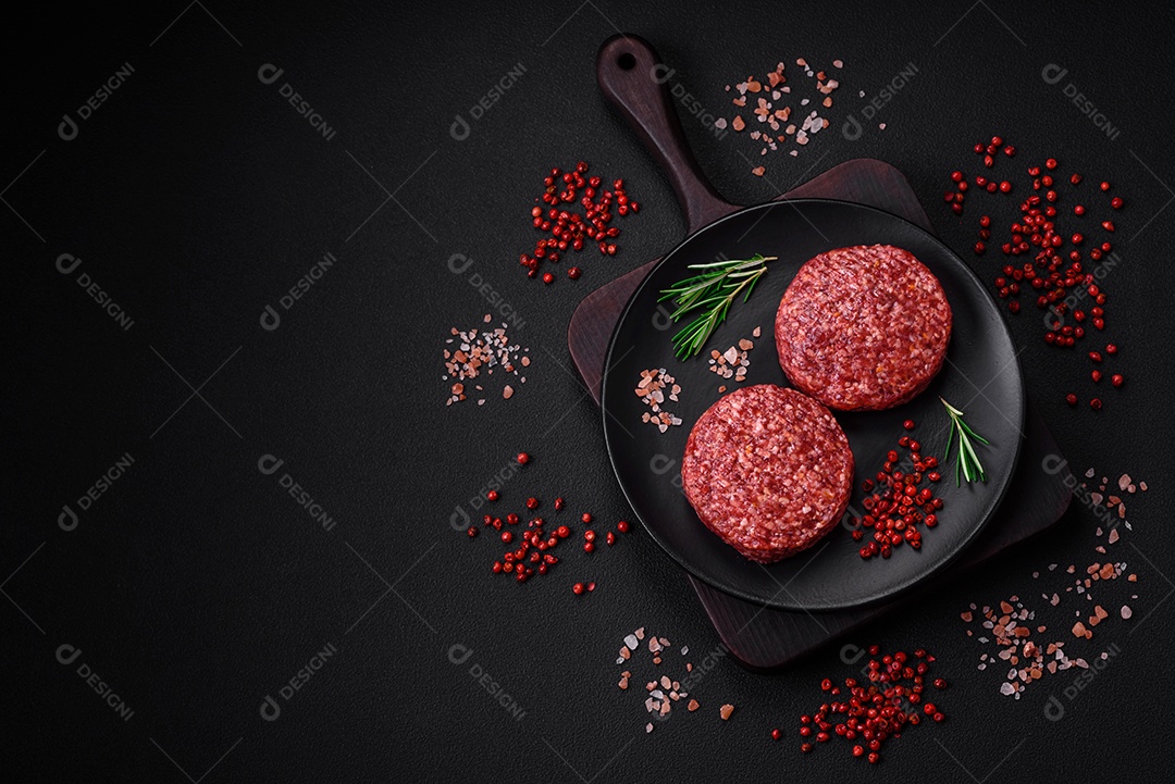 Hambúrguer de carne moída crua fresca com sal e especiarias em fundo de concreto texturizado