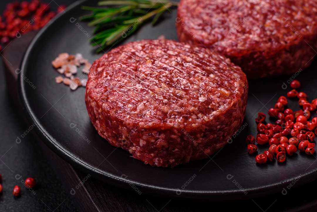 Hambúrguer de carne moída crua fresca com sal e especiarias em fundo de concreto texturizado
