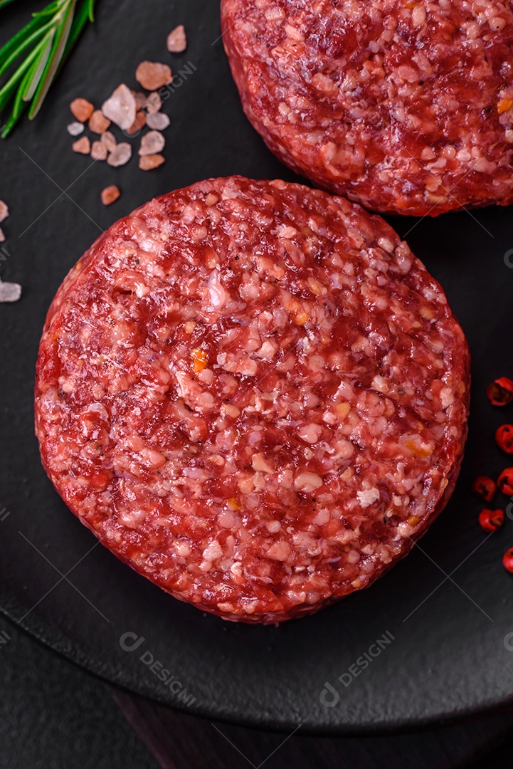 Hambúrguer de carne moída crua fresca com sal e especiarias em fundo de concreto texturizado