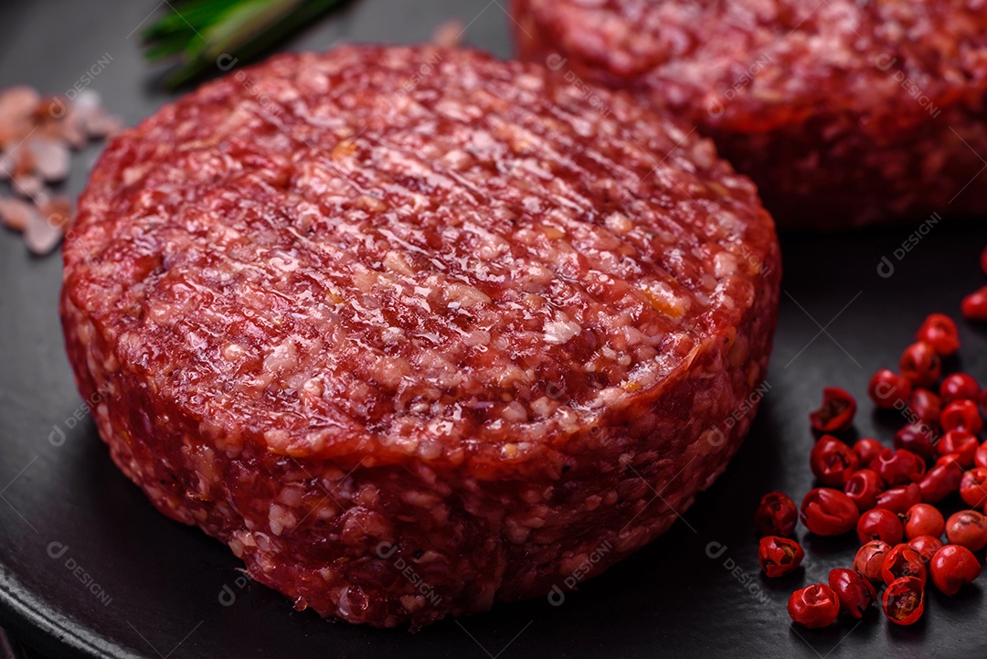 Hambúrguer de carne moída crua fresca com sal e especiarias em fundo de concreto texturizado