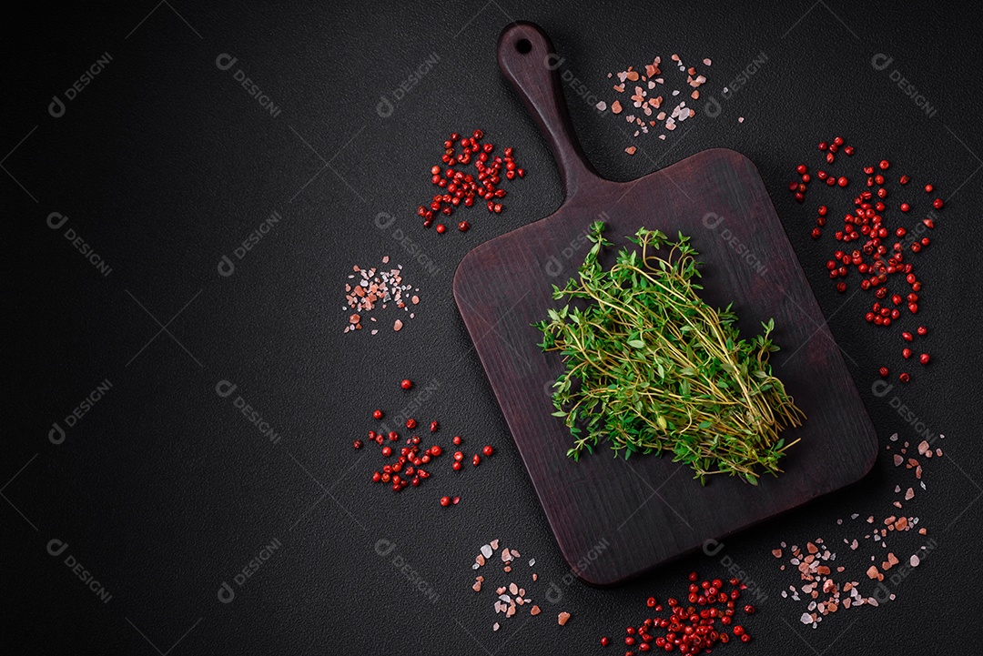 Tábua de madeira vazia com tomilho, especiarias, sal e ervas em fundo escuro de concreto