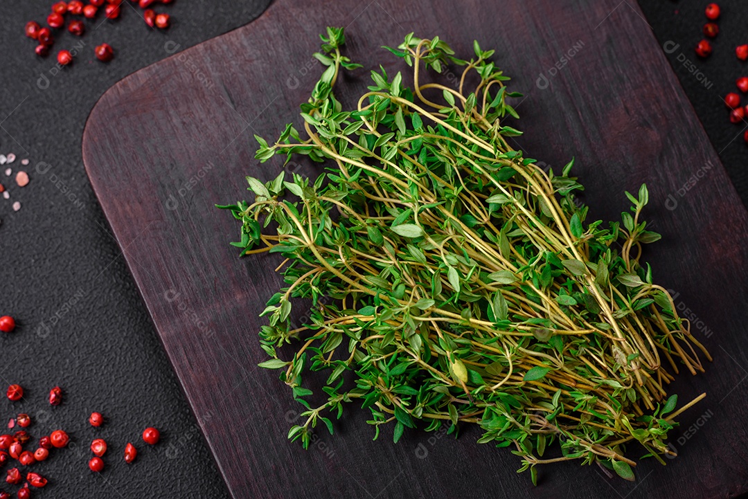 Tábua de madeira vazia com tomilho, especiarias, sal e ervas em fundo escuro de concreto