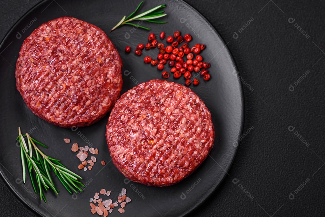 Hambúrguer de carne moída crua fresca com sal e especiarias em fundo de concreto texturizado