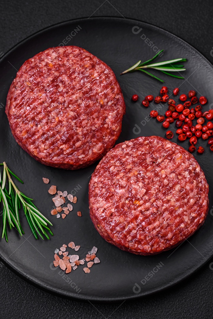 Hambúrguer de carne moída crua fresca com sal e especiarias em fundo de concreto texturizado