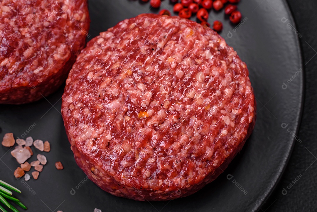Hambúrguer de carne moída crua fresca com sal e especiarias em fundo de concreto texturizado