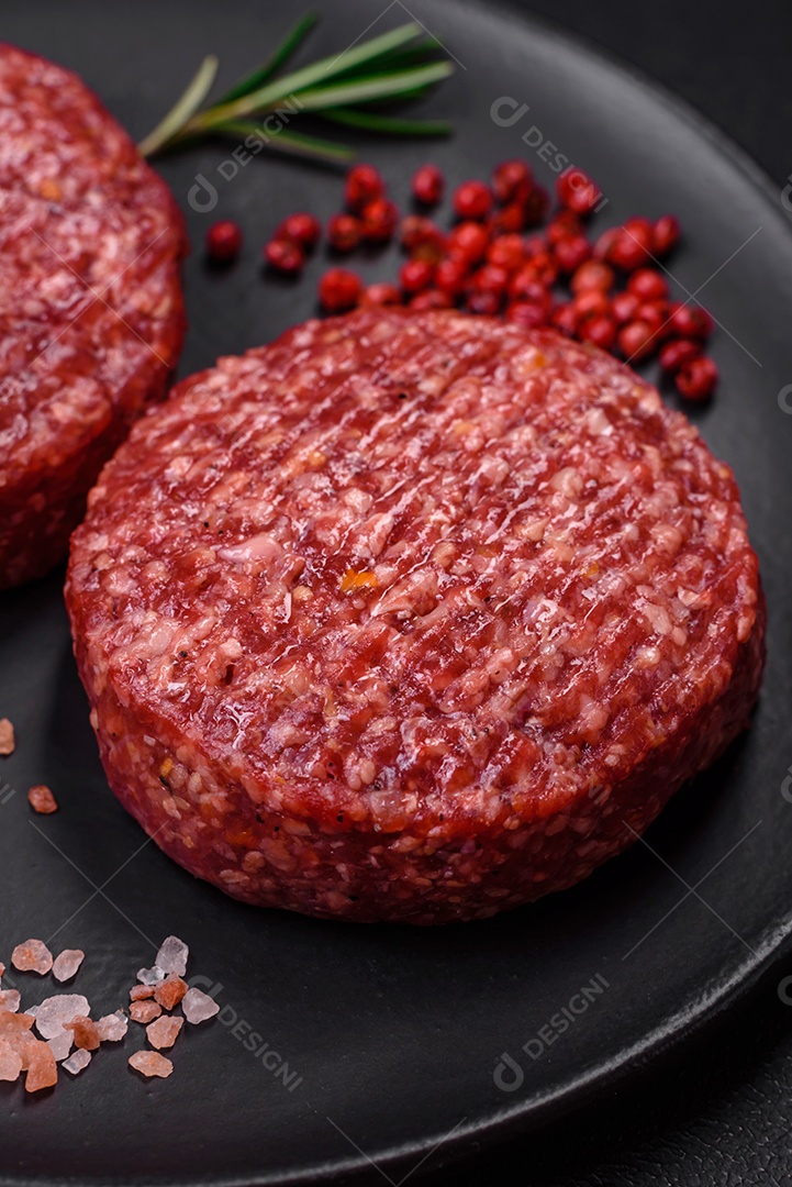 Hambúrguer de carne moída crua fresca com sal e especiarias em fundo de concreto texturizado
