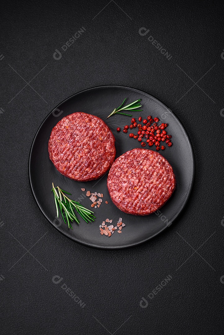 Hambúrguer de carne moída crua fresca com sal e especiarias em fundo de concreto texturizado