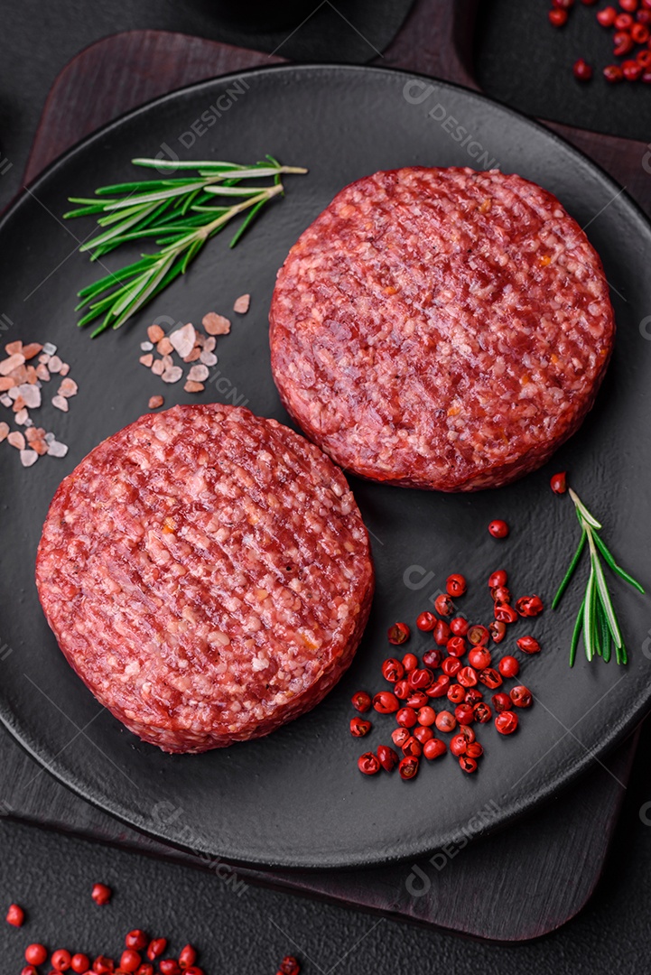Hambúrguer de carne moída crua fresca com sal e especiarias em fundo de concreto texturizado