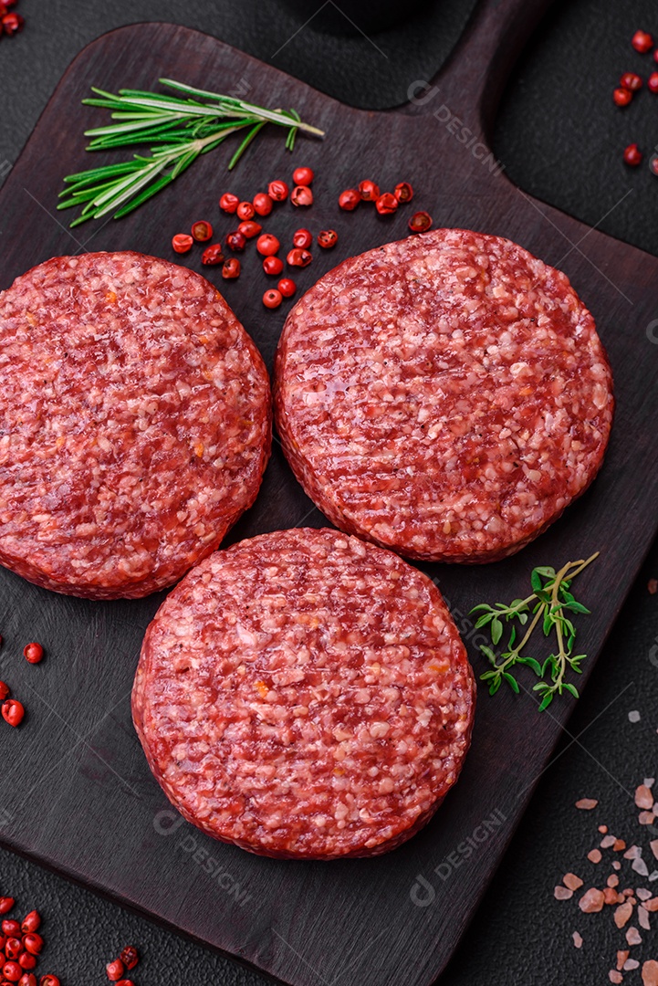Hambúrguer de carne moída crua fresca com sal e especiarias em fundo de concreto texturizado