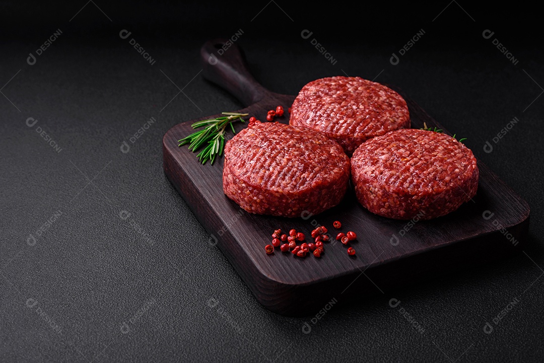 Hambúrguer de carne moída crua fresca com sal e especiarias em fundo de concreto texturizado