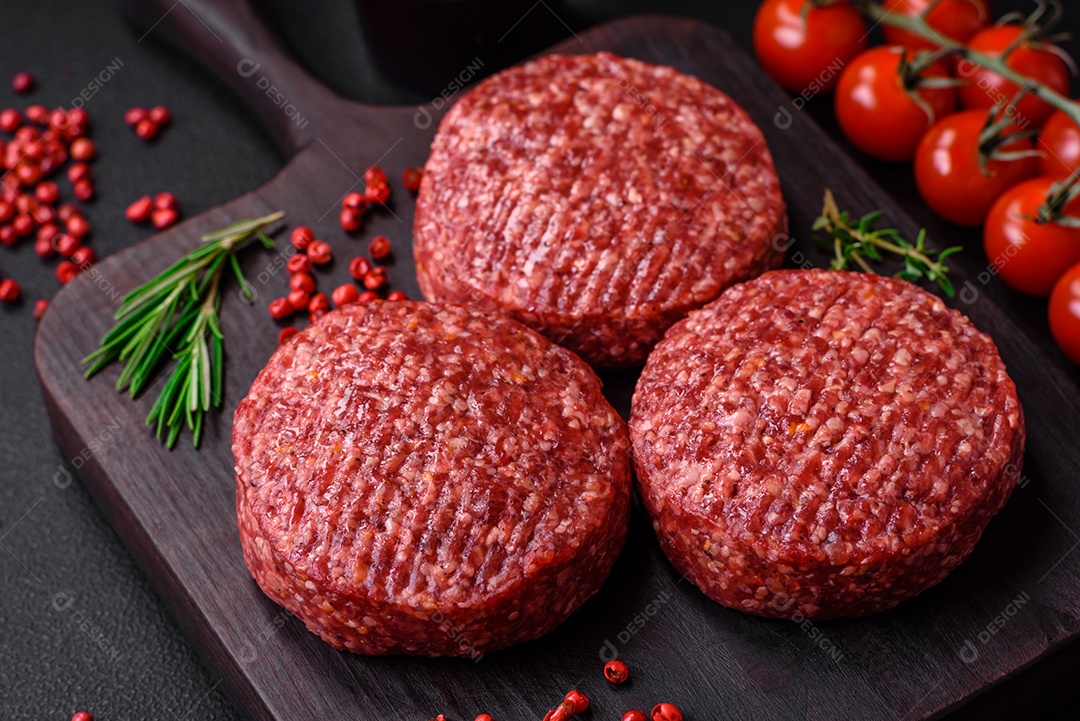 Hambúrguer de carne moída crua fresca com sal e especiarias em fundo de concreto texturizado