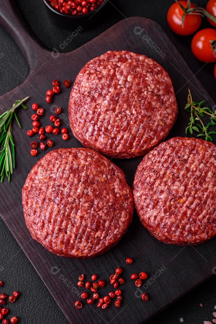 Hambúrguer de carne moída crua fresca com sal e especiarias em fundo de concreto texturizado