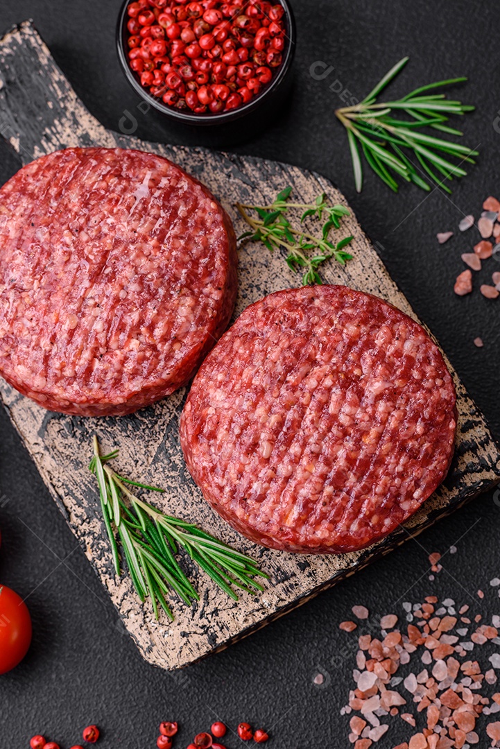 Hambúrguer de carne moída crua fresca com sal e especiarias em fundo de concreto texturizado