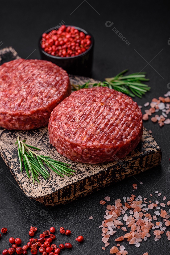 Hambúrguer de carne moída crua fresca com sal e especiarias em fundo de concreto texturizado