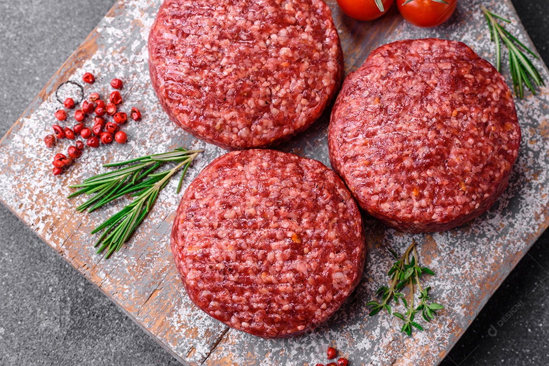 Hambúrguer de carne moída crua fresca com sal e especiarias em fundo de concreto texturizado