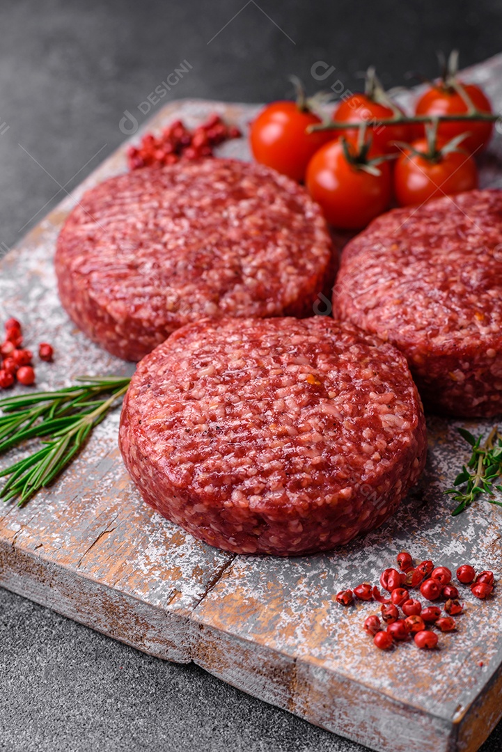 Hambúrguer de carne moída crua fresca com sal e especiarias em fundo de concreto texturizado