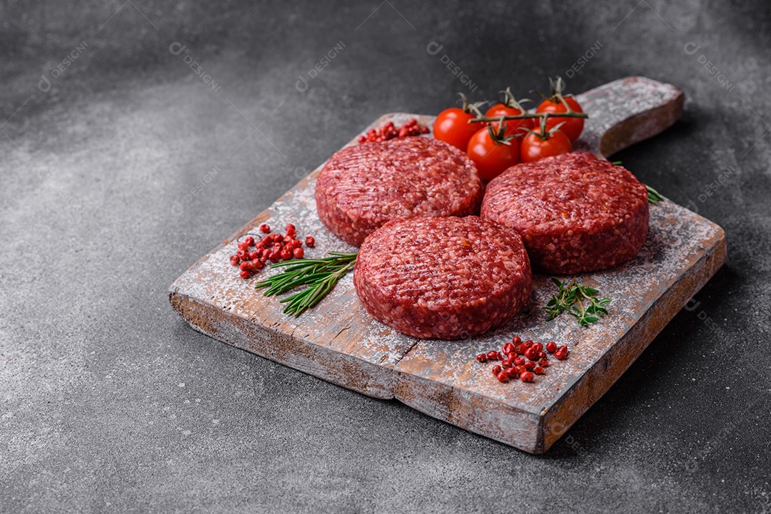 Hambúrguer de carne moída crua fresca com sal e especiarias em fundo de concreto texturizado