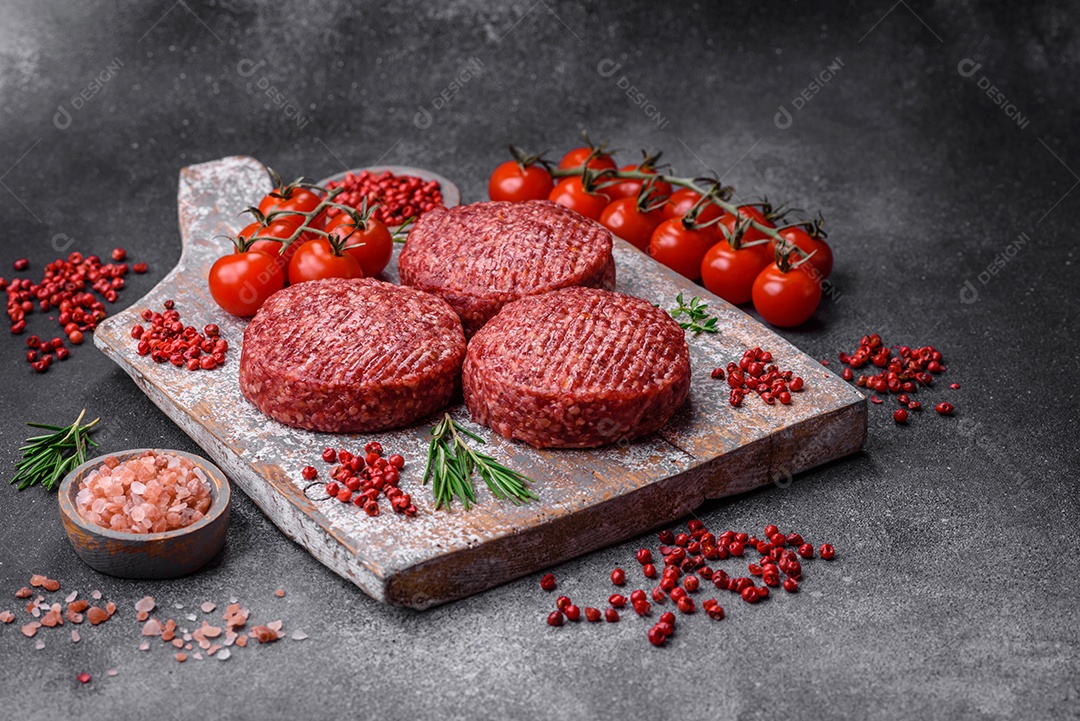 Hambúrguer de carne moída crua fresca com sal e especiarias em fundo de concreto texturizado