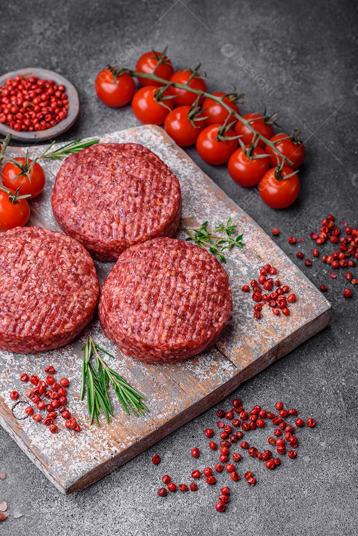 Hambúrguer de carne moída crua fresca com sal e especiarias em fundo de concreto texturizado
