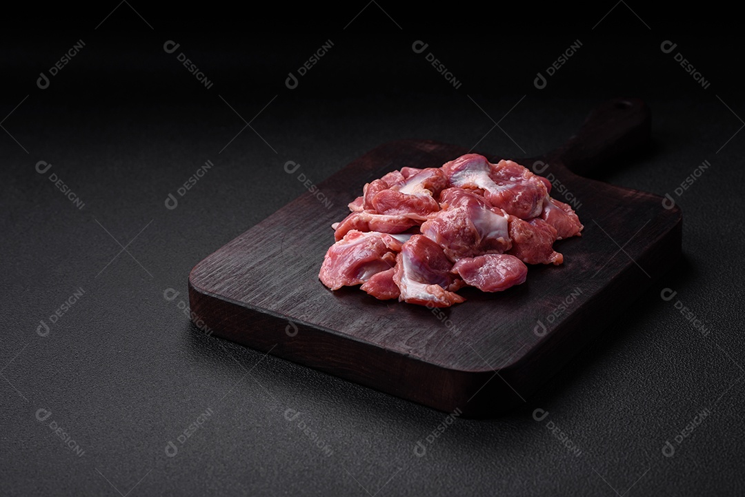 Corações crus de frango ou peru com sal, especiarias e ervas sobre um fundo de concreto texturizado