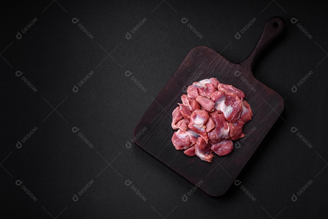 Corações crus de frango ou peru com sal, especiarias e ervas sobre um fundo de concreto texturizado