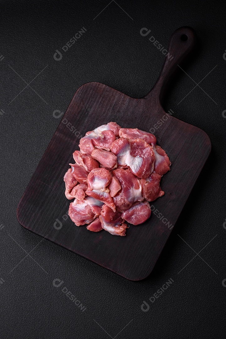 Corações crus de frango ou peru com sal, especiarias e ervas sobre um fundo de concreto texturizado