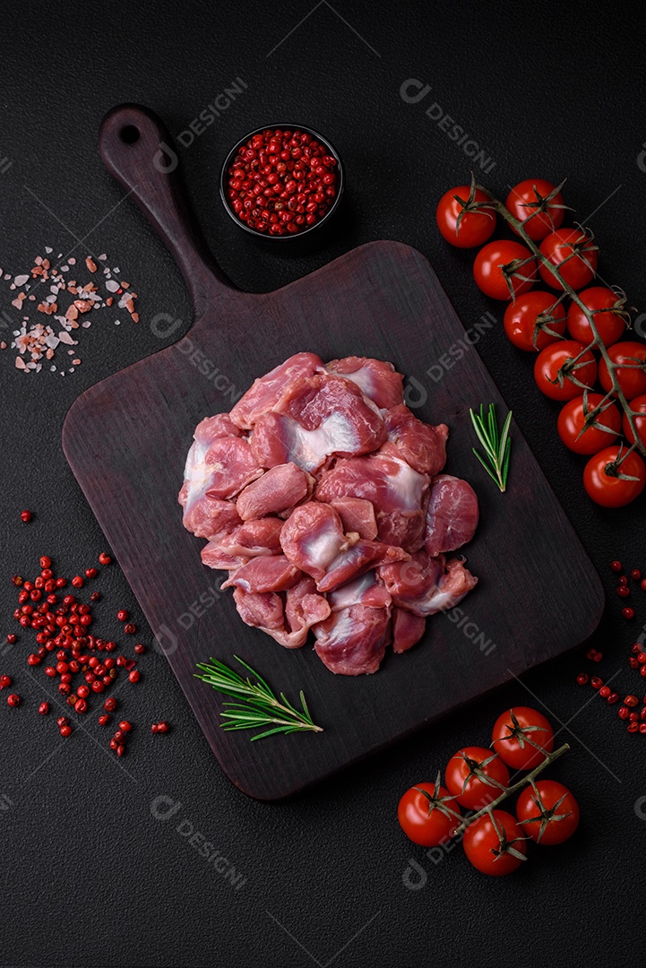 Corações crus de frango ou peru com sal, especiarias e ervas sobre um fundo de concreto texturizado