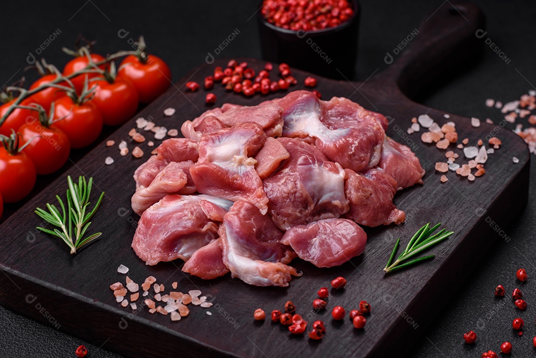 Corações crus de frango ou peru com sal, especiarias e ervas sobre um fundo de concreto texturizado