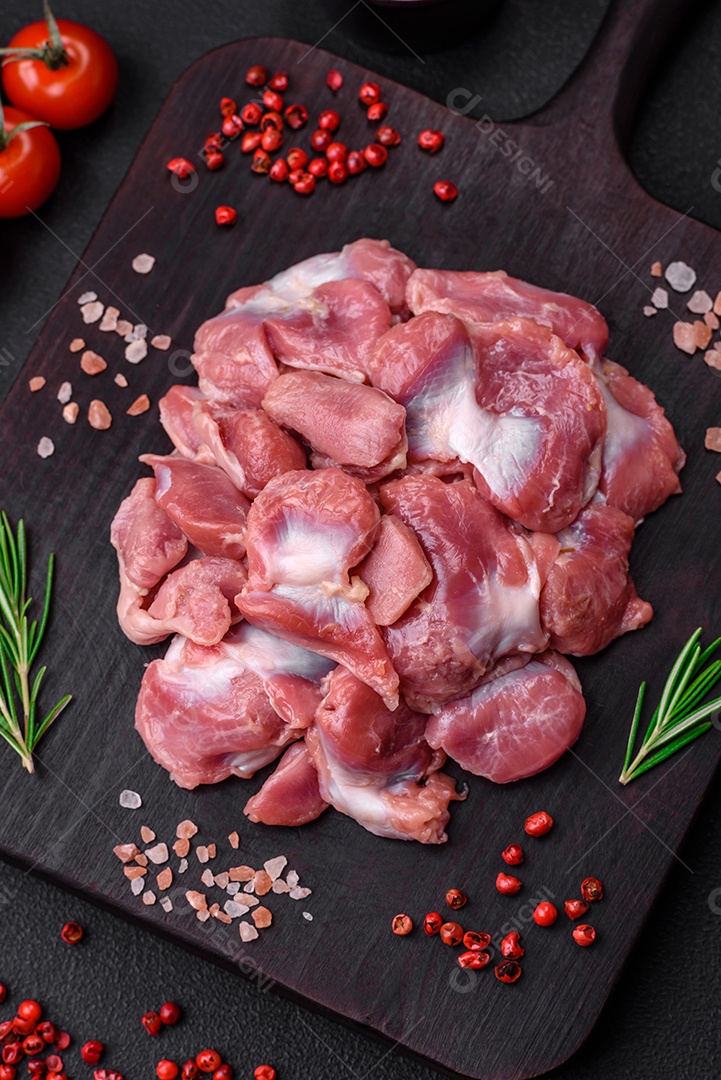 Corações crus de frango ou peru com sal, especiarias e ervas sobre um fundo de concreto texturizado