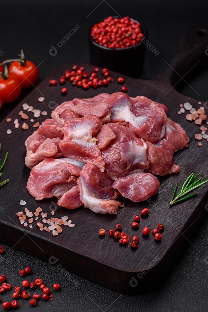 Corações crus de frango ou peru com sal, especiarias e ervas sobre um fundo de concreto texturizado