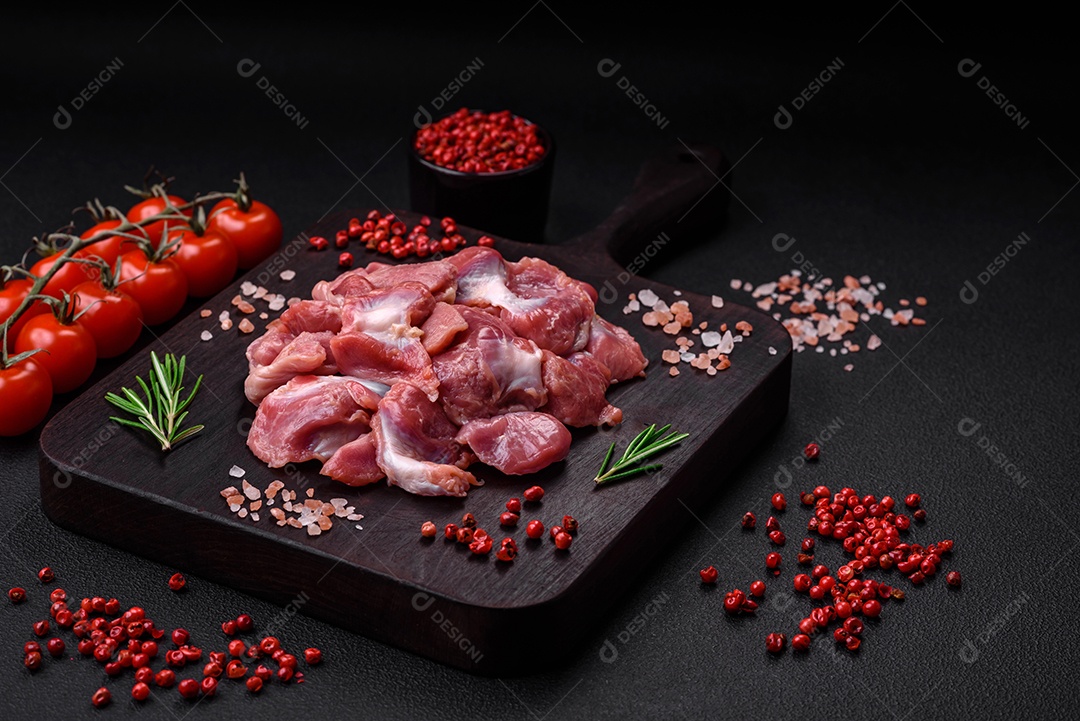 Corações crus de frango ou peru com sal, especiarias e ervas sobre um fundo de concreto texturizado