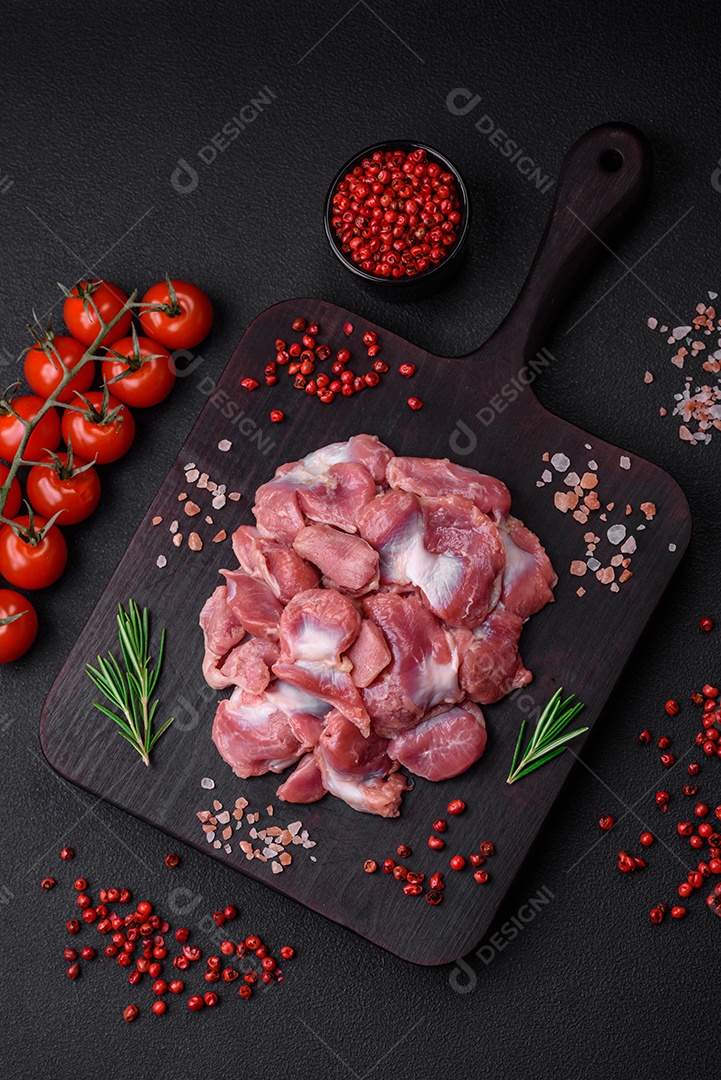 Corações crus de frango ou peru com sal, especiarias e ervas sobre um fundo de concreto texturizado