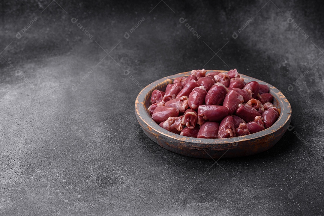 Corações crus de frango ou peru com sal, especiarias e ervas sobre um fundo de concreto texturizado