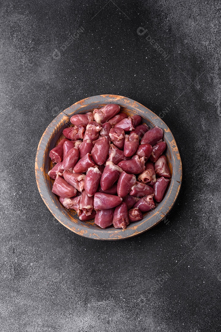 Corações crus de frango ou peru com sal, especiarias e ervas sobre um fundo de concreto texturizado