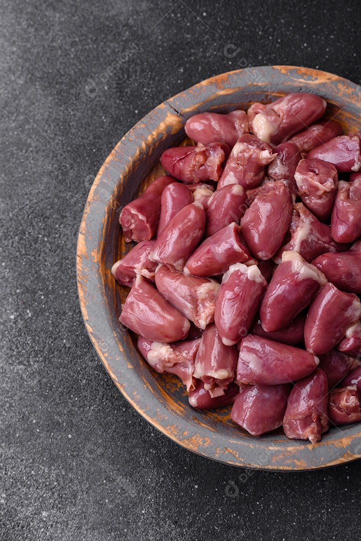 Corações crus de frango ou peru com sal, especiarias e ervas sobre um fundo de concreto texturizado