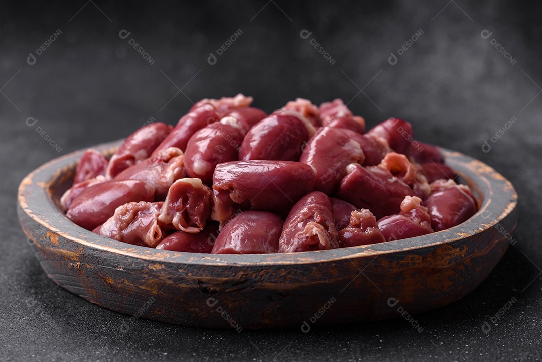 Corações crus de frango ou peru com sal, especiarias e ervas sobre um fundo de concreto texturizado