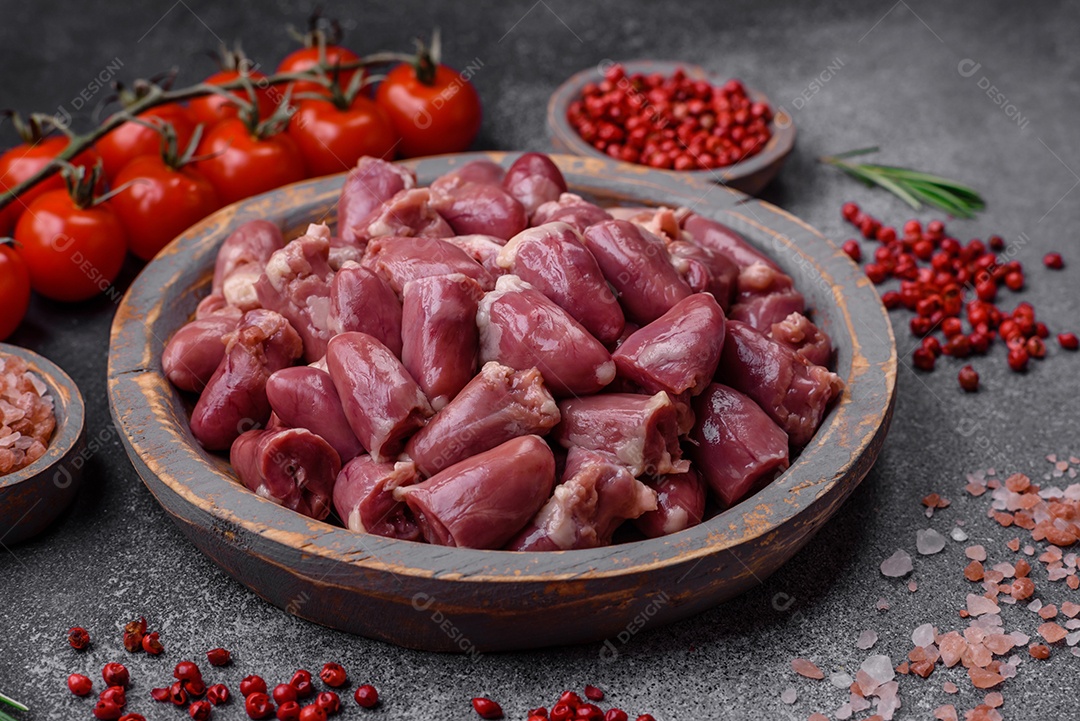 Corações crus de frango ou peru com sal, especiarias e ervas sobre um fundo de concreto texturizado