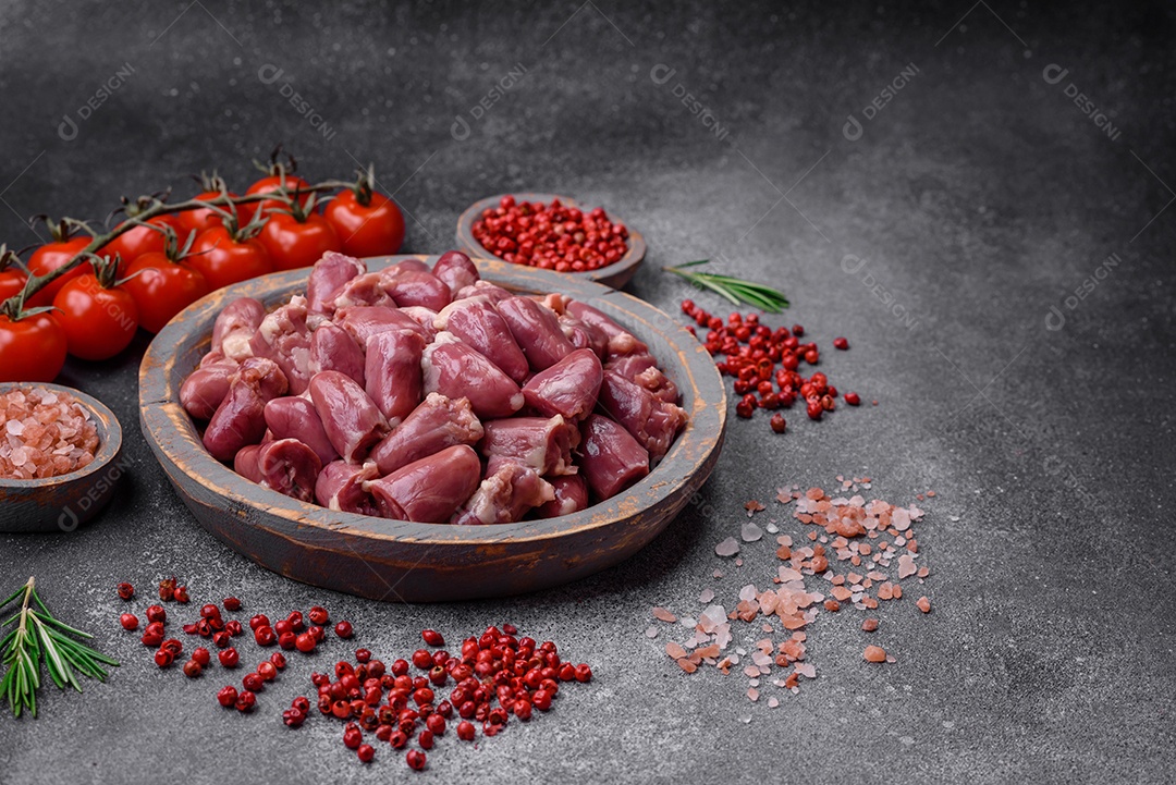 Corações crus de frango ou peru com sal, especiarias e ervas sobre um fundo de concreto texturizado